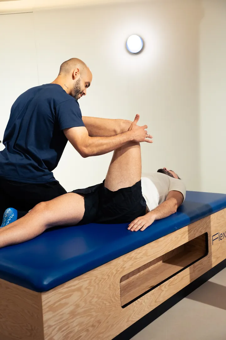 Le flexologue étire la jambe d’un client allongé sur la table.