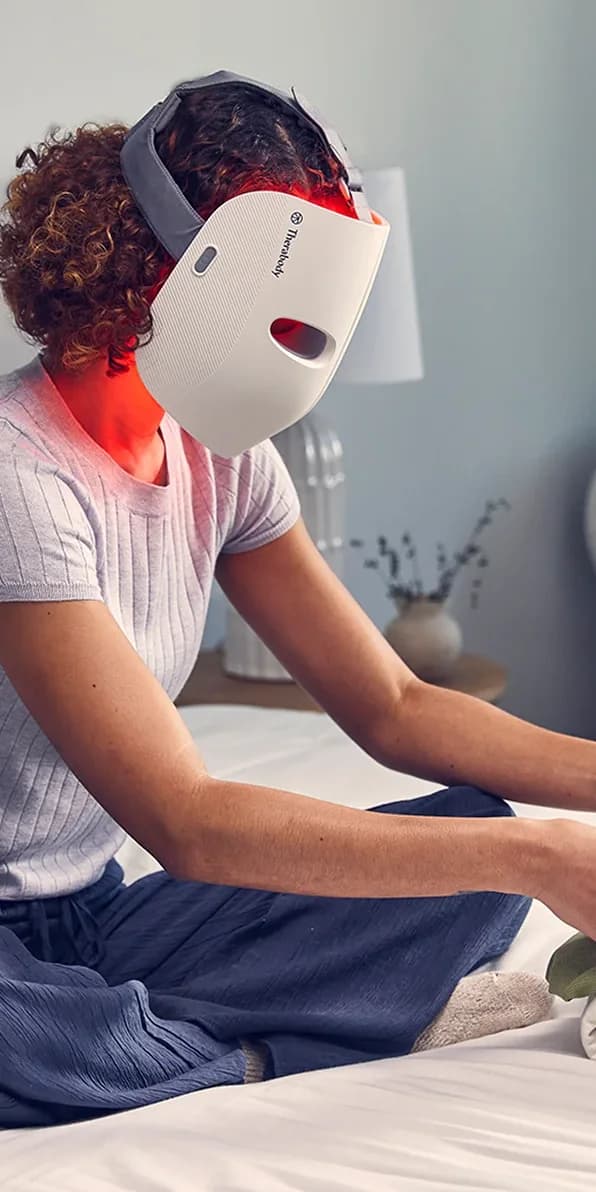 Une femme porte un masque de luminothérapie allumé.