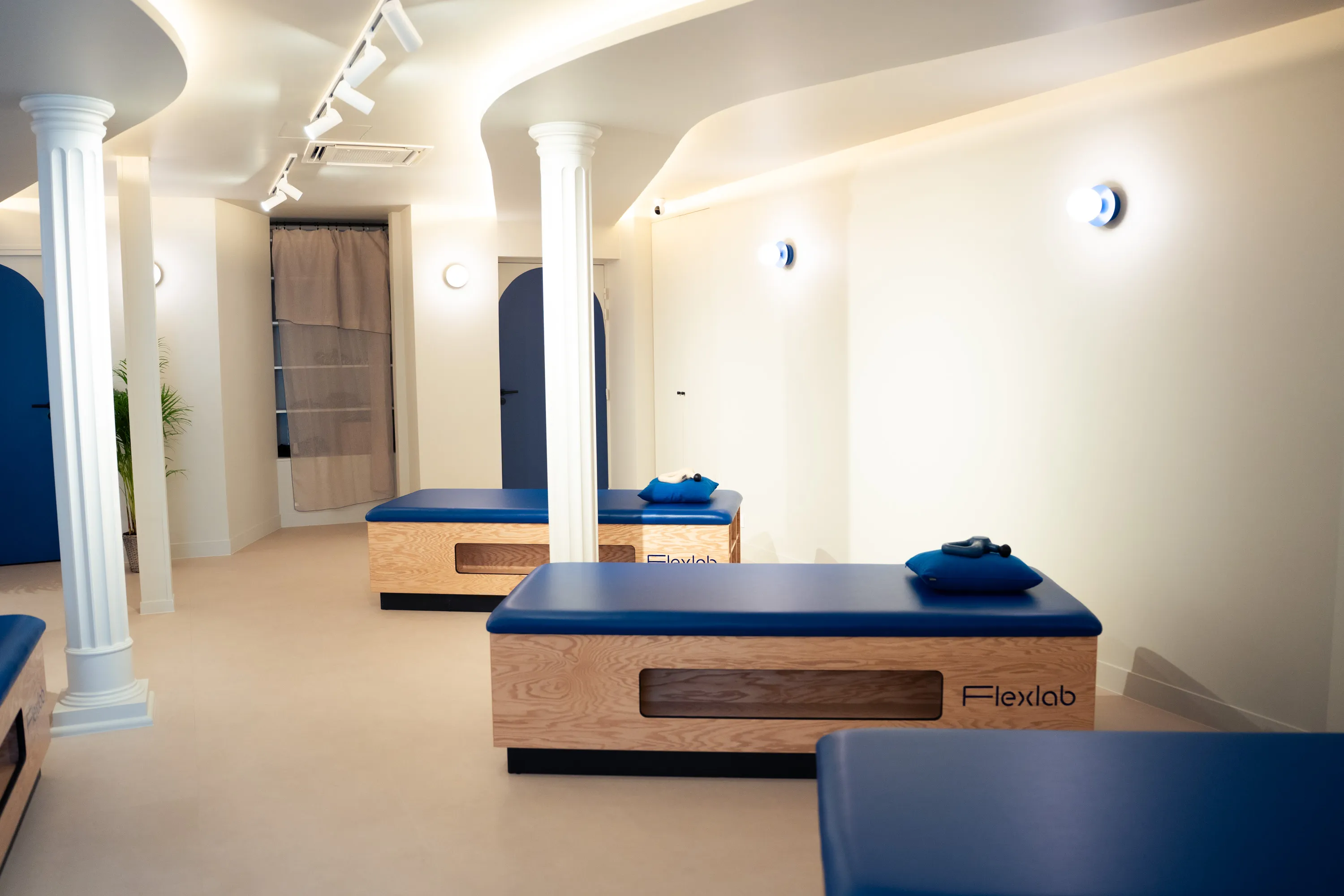 La salle du studio Flexlab Sentier : deux colonnes, les tables de stretching et le plafond rétroéclairé